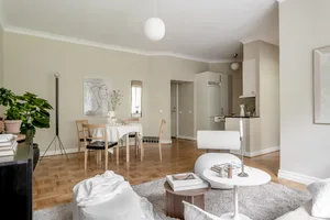A modern minimalist living room featuring wooden furniture and a white carpet.