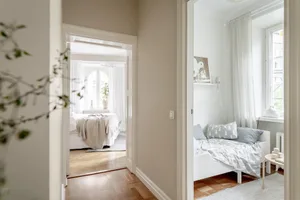 A modern minimalist bedroom with white furniture and wooden floors.