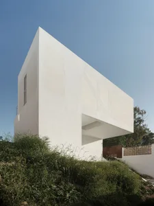 現代極簡白色盒子建築，採用混凝土外牆，坐落於岩石山坡上。