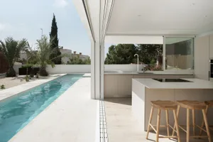 A modern minimalist poolside kitchen featuring an integrated design with sleek lines and natural lighting.