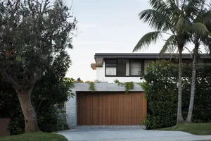 Modern residential building with a concrete and wooden facade, featuring a garage door.
