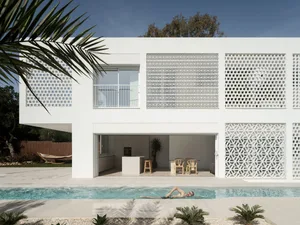 Modern residential building with a white, concrete exterior featuring large windows and geometric patterns.