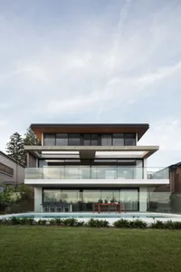 Two-story modern residential building with glass and concrete exterior materials