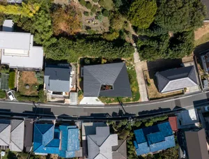 An aerial view of a modern residential roof surrounded by trees and foliage.