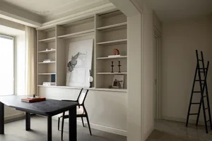 A clean, minimalist home office setup featuring a black table and chair, a white storage unit with shelves, and a large windo