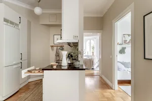 A modern kitchen with white cabinetry, wooden countertops, and beige accents.