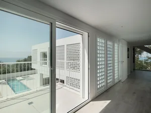 A modern interior with large white glass windows and a pool view.