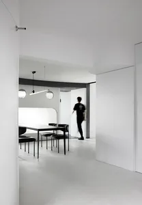 A modern minimalistic office space featuring a white concrete interior and sleek black office furniture.