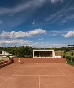 A clay tennis court with a modern architectural building in the background.
