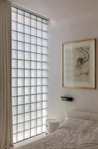 Bedroom with frosted glass block wall and minimalist decor.