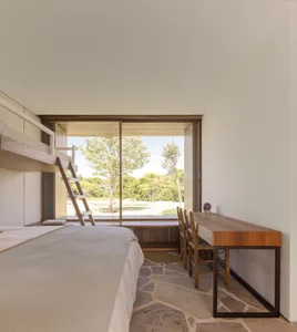 Minimalist bedroom with wooden furniture, including a bunk bed and a desk with chairs.
