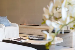 Modern minimalist living room featuring a marble fireplace and coffee table with flowers.