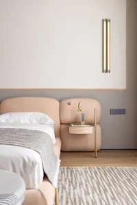 A modern bedroom featuring a pastel pink leather bed with a soft fur blanket, a brass side table, and a sleek lamp on the wal