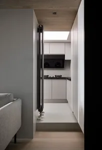 A modern kitchen with white cabinets, black appliances, and concrete flooring and countertops.