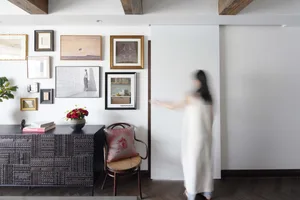 A modern living room with wooden furniture, a plant, and a decorated wall.