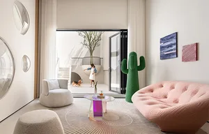 Modern living room with a white armchair, a pink couch, and a green cactus sculpture