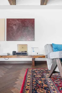A modern living room featuring wooden furniture and a patterned rug.