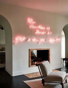 A modern living room featuring neon lights spelling out literature-related phrases above a fireplace.