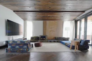 A modern living room with a wooden floor, ceiling, and furniture.