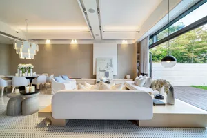 Modern minimalist living room with sleek white furniture, a unique jack-leg stool arrangement, and elegant wall art incorpora