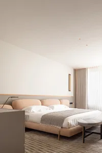 Modern bedroom featuring soft, neutral-toned bedding and furniture.