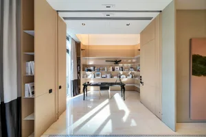 A modern office space featuring wooden panels and a sleek desk with a lamp and books.