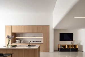Modern residential kitchen with wooden cabinets, a kitchen island, and a TV stand.