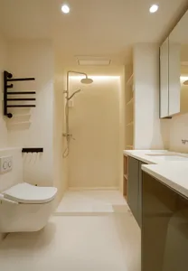 A minimalist bathroom with white tiled flooring and walls, featuring a toilet, a walk-in shower, and a sleek sink counter wit