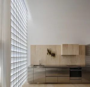 Modern minimalist kitchen featuring custom glass block partitions and stainless steel cabinetry and appliances.