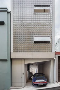 Modern building exterior featuring glass blocks and a blue sports car parked in the garage.