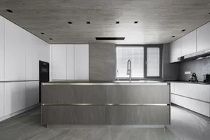 Minimalist kitchen with gray and white color scheme and concrete countertops.