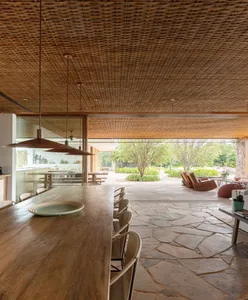 Minimalist patio area with wooden ceiling and furniture, surrounded by natural greenery.