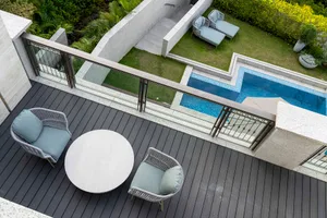 Modern patio with a round table and two chairs, featuring a concrete deck, glass railings, and a concrete wall with a glass w