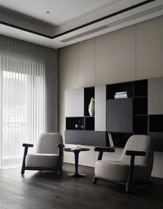 A modern minimalist living room featuring two patterned armchairs, a wooden floor, and a large window with sheer curtains.