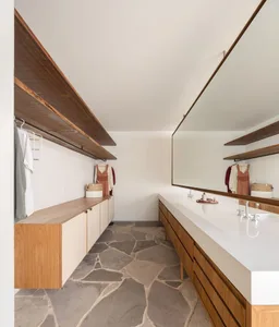 Modern closet with wooden shelving and countertops, featuring a mix of light and dark wood, and a stone or terrazzo floor.