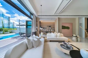 Living room with white sofas, coffee table, and a view of a pool and blue sky.
