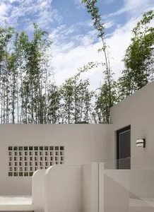 極簡建築外觀，搭配白色牆面、綠意植栽，以及混凝土與玻璃材質。