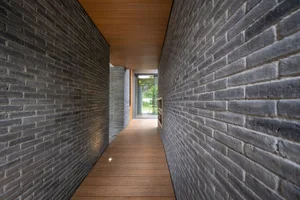 A modern interior corridor with brick walls and wooden flooring.
