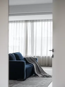 A minimalist living room with a blue sofa, gray throw blanket, and textured cushions.