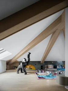 A modern playroom with wooden beams, featuring a black gorilla sculpture and colorful rug.