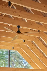 A modern industrial ceiling with wooden beams, a ceiling fan, and a large window.