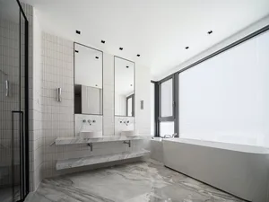 Modern minimalist bathroom with marble finishes and a large window.