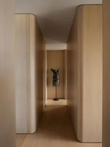 A minimalist hallway with wooden walls and a metallic dress sculpture.