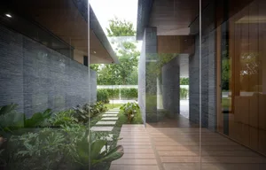 A modern architectural space featuring brick walls and glass walkways surrounded by greenery.