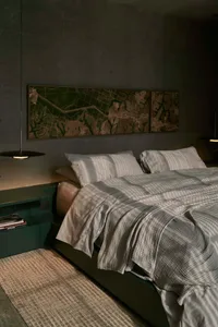 A modern bedroom with gray textiles and a concrete floor.