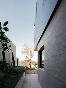 Concrete and stone building facade with plants and a tree.
