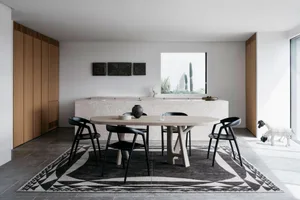Modern dining room featuring a wooden table with a concrete base, surrounded by black chairs and positioned on a geometric ru