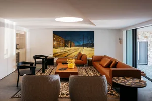 A modern living room featuring a leather couch and a large framed painting of a landscape.