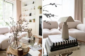 A modern living room featuring a glass vase with dried flowers, a ceramic lamp, and candles on a glass coffee table, with whi