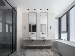 Modern bathroom with marble walls and white tiles, featuring two sinks and mirrors.